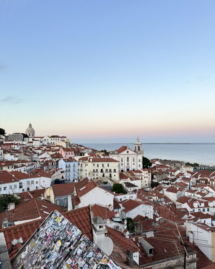 Lisbon in March: 10 Things To Do (Spring is Here) 9 Beautiful panoramic view of Lisbon's historic rooftops with the Atlantic Ocean in the background during spring.