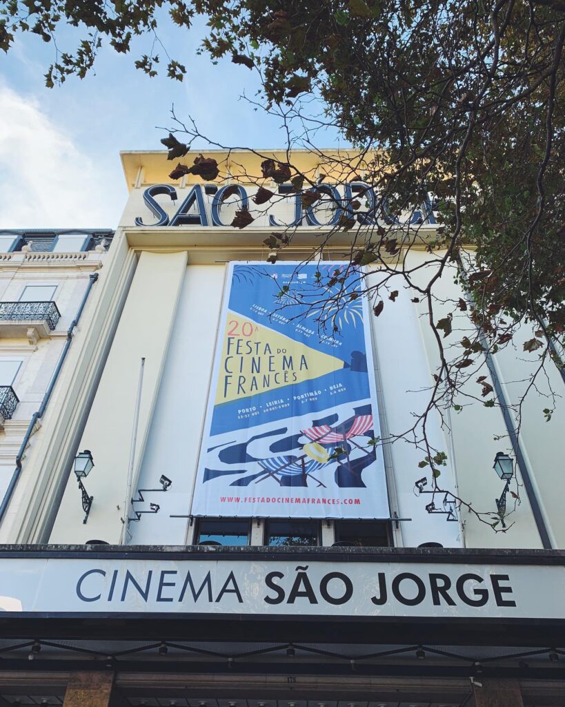 Lisbon in March: 10 Things To Do (Spring is Here) 7 Historic Lisbon cinema São Jorge showcasing a vibrant poster for the French Cinema Festival, surrounded by lush trees and classic architecture, perfect for springtime cultural outings.