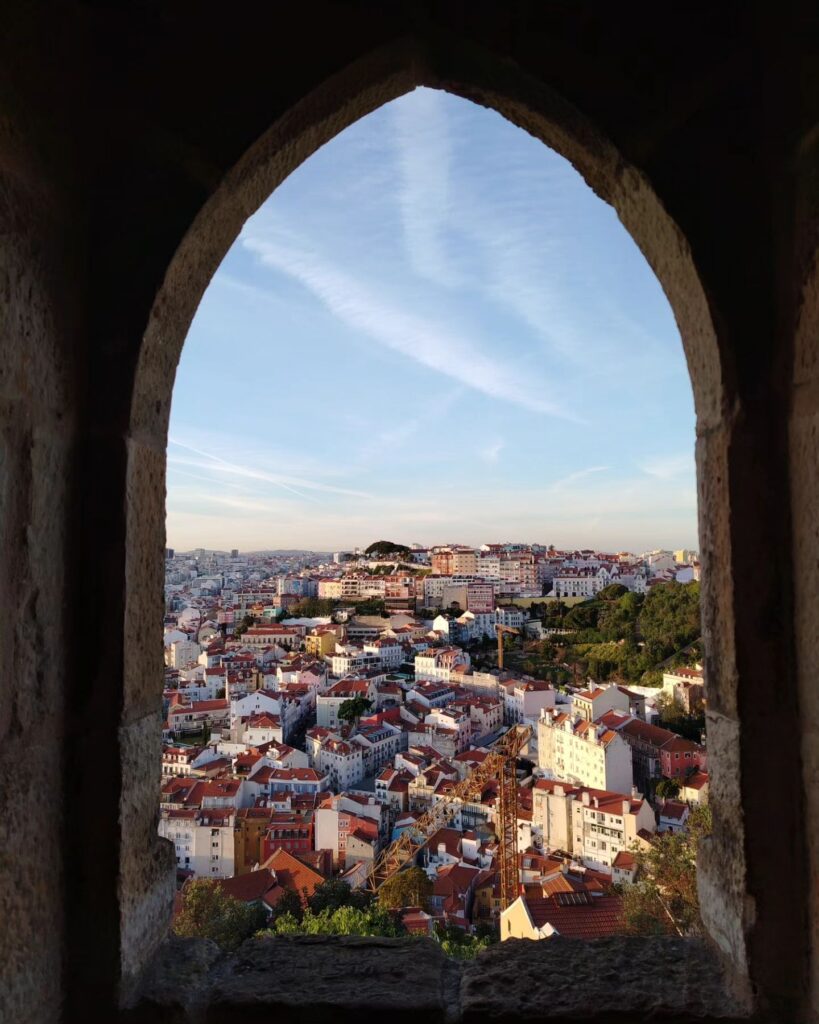 Lisbon in April: The Perfect Time To Visit 8 Panoramic view of Lisbon's historic neighborhoods and colorful rooftops from a castle window during spring. Perfect for travel and sightseeing in Portugal.
