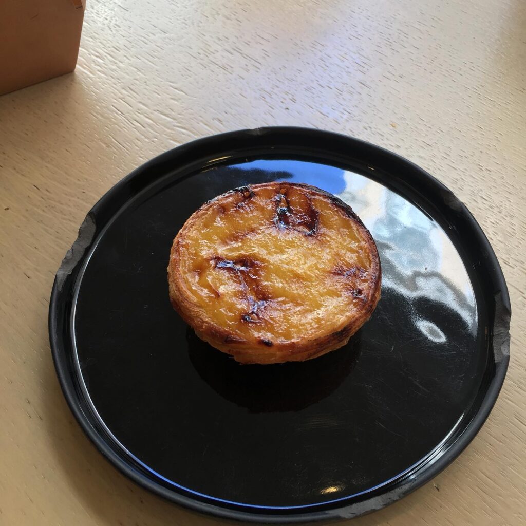 7 Best Pastel de Nata in Lisbon (I've Tried Them All Now) 7 Golden Portuguese egg tart pastry on black plate at LisboaVibes, showcasing authentic Lisbon desserts. Perfect for exploring Lisbon's rich pastry culture and culinary delights. Located in Lisbon, Portugal.