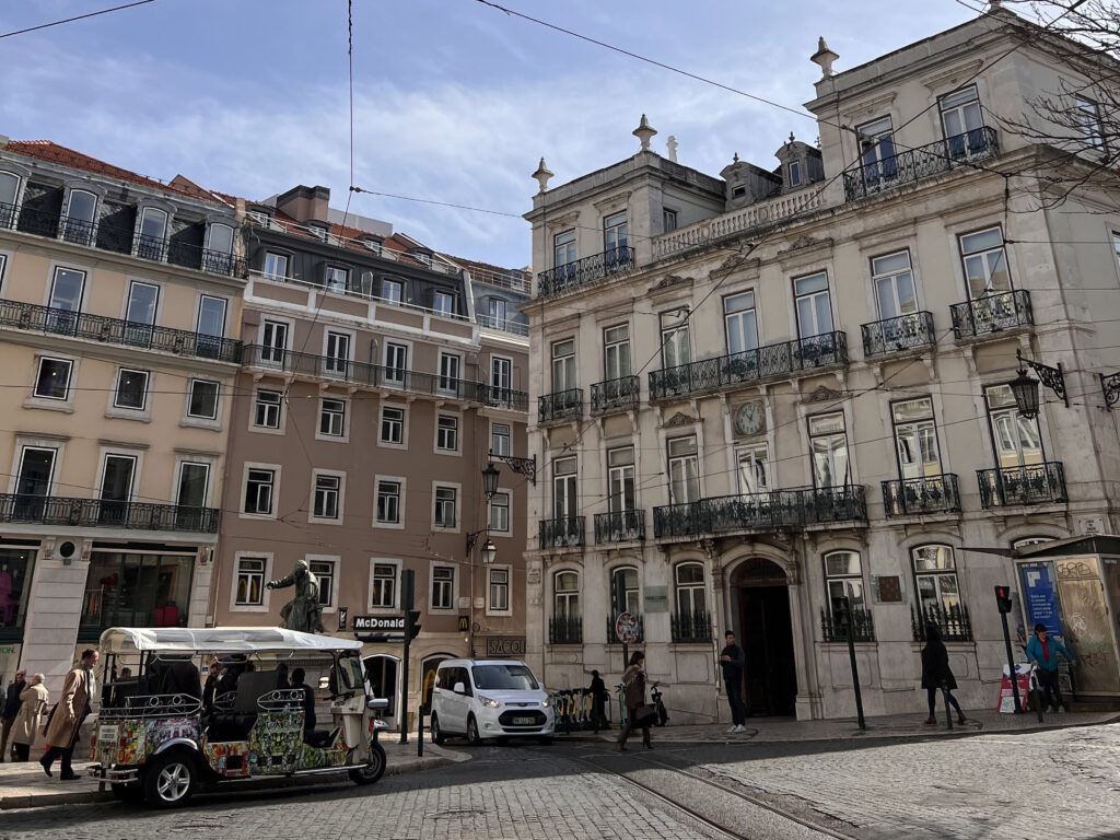Lisbon Neighborhoods: Local's Guide to Where to Visit 4 Historic buildings and lively street scene in Lisbon, Portugal, showcasing classic architecture, local shops, and pedestrians enjoying a vibrant city atmosphere.