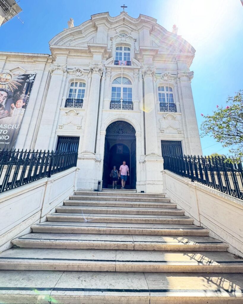 Alfama in Lisbon: A Tourist Guide 10 Alfama Church in Lisbon, Portugal, showcasing Baroque architecture with ornate details and a grand entrance, set against a bright blue sky on a sunny day.