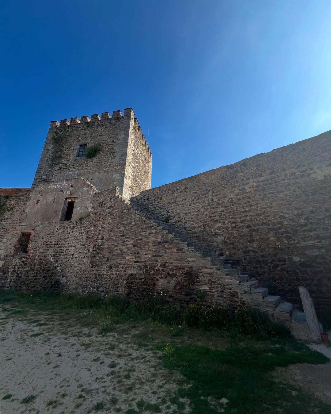 21 Amazing Castles in Lisbon and Its Surroundings 20 Ancient stone castle tower in Lisbon, Portugal under a clear blue sky, showcasing historical architecture and scenic views, perfect for travel and cultural exploration.