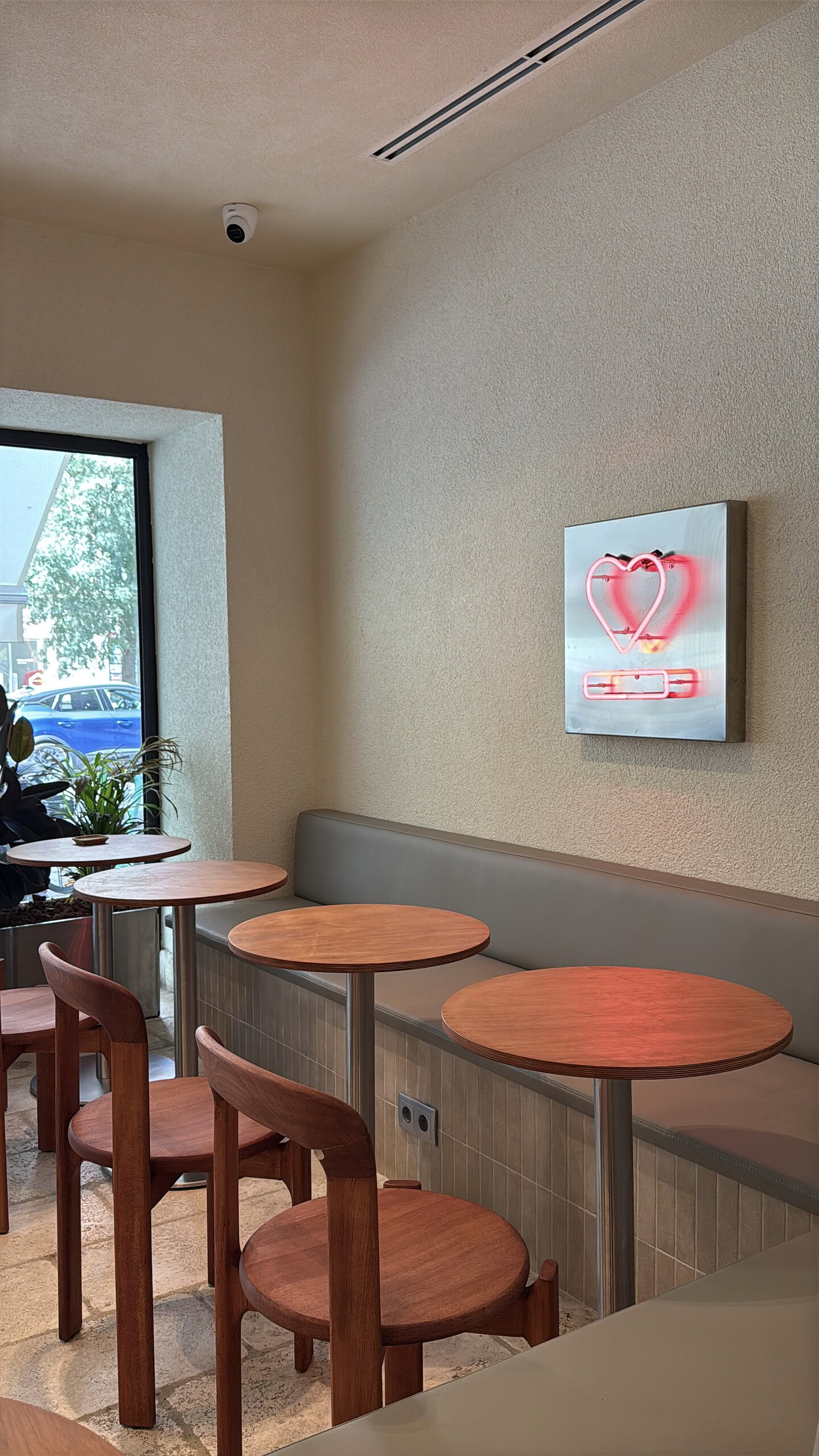 Bright and inviting coffee shop corner in Lisbon with wooden tables and chairs, natural light from the window, perfect for enjoying a cup of coffee in a relaxed atmosphere.