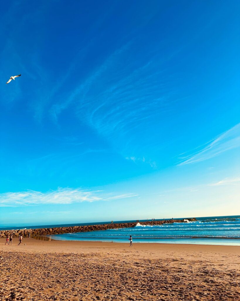 12 Best Beaches in Lisbon (Tourism Guide) 2 Relaxing Lisbon beach with golden sands, calm waters, and a clear blue sky, ideal for sunbathing, swimming, and seaside activities.