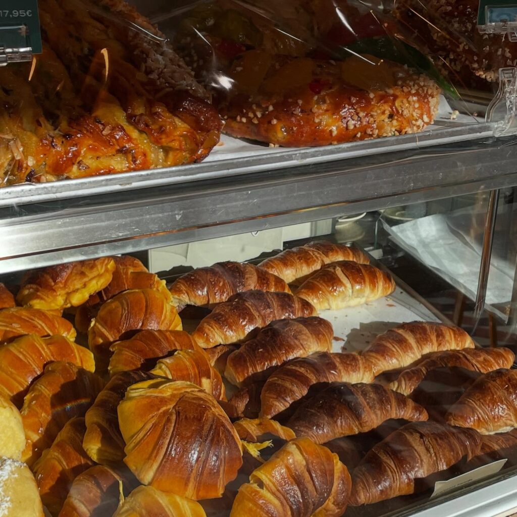 6 Best Portuguese Restaurants in Lisbon (Local & Authentic) 11 Buttery croissants and assorted pastries in a bakery display case in Lisbon, Portugal, showcasing delicious baked goods, perfect for breakfast or a snack during LisbonVibes exploration.