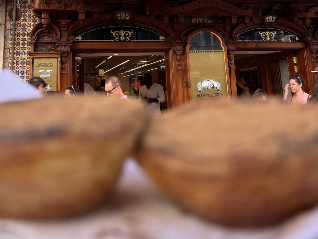 Lisbon Food Guide: What to Eat + Where to Eat (Local Tips + Map) 6 1. Traditional Portuguese pastry shop in Lisbon with ornate wooden exterior and bustling interior, perfect for enjoying authentic local treats.