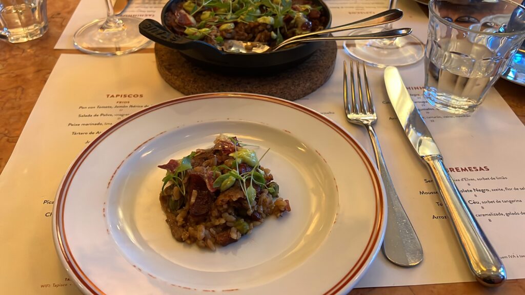 6 Best Portuguese Restaurants in Lisbon (Local & Authentic) 4 1. Delicious Portuguese-style rice dish with fresh greens and tender meat, served elegantly on a vintage plate at a Lisbon restaurant.