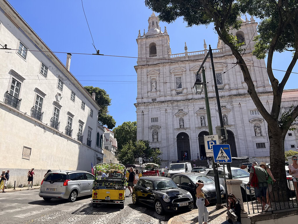 Historic Graça Church in Lisbon with street scene and parked cars, capturing the neighborhood's charm and architecture.