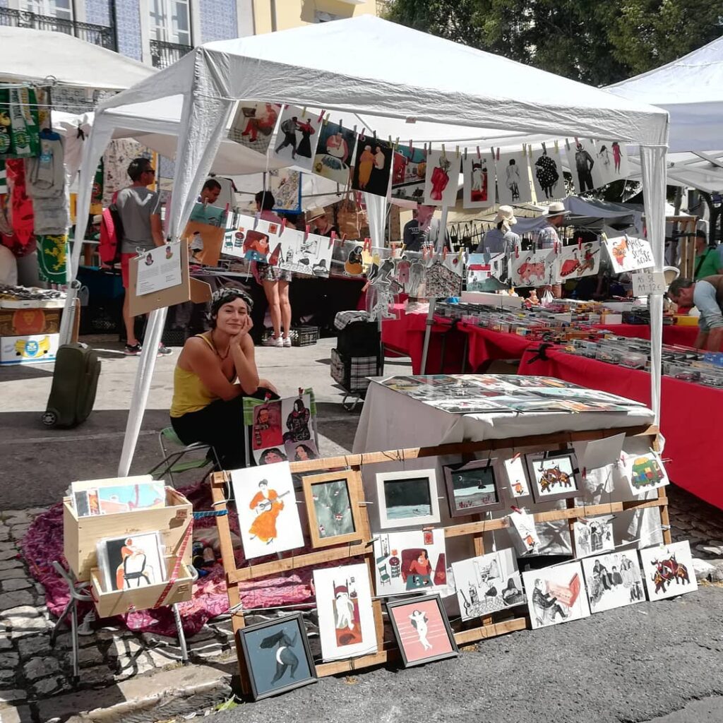 Graça Lisbon: A Neighborhood Guide 4 Vibrant art display at Graça Lisbon market showcasing local artists' work, including paintings, illustrations, and crafts, perfect for visitors exploring Lisbon's artistic neighborhoods.