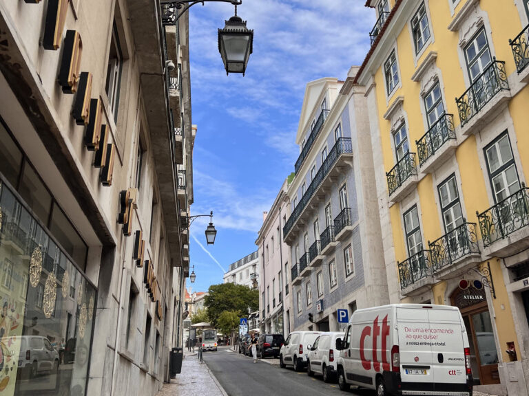Vibrant Lisbon neighborhood street with colorful buildings, traditional balconies, and cobblestone pavement, showcasing the lively atmosphere of Bairro Alto in Lisbon.